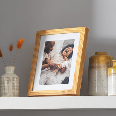 Oak photo frame on shelf with family portrait