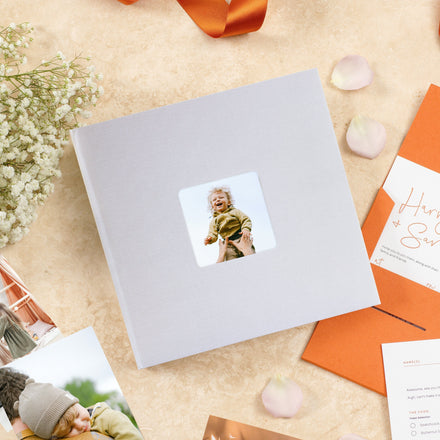 Aztec photo album in grey surrounded by an invitation, flowers and photographs