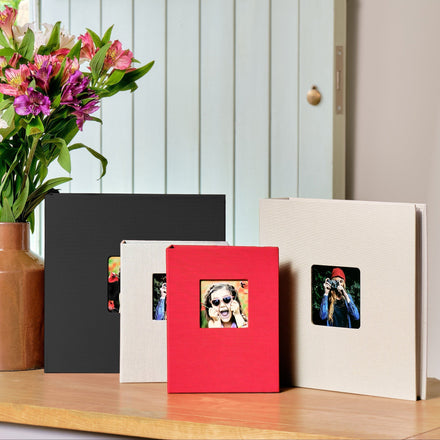 A collection of Aztec photo albums in different colours displayed on a wooden surface, with a photo of a flower vase in the background